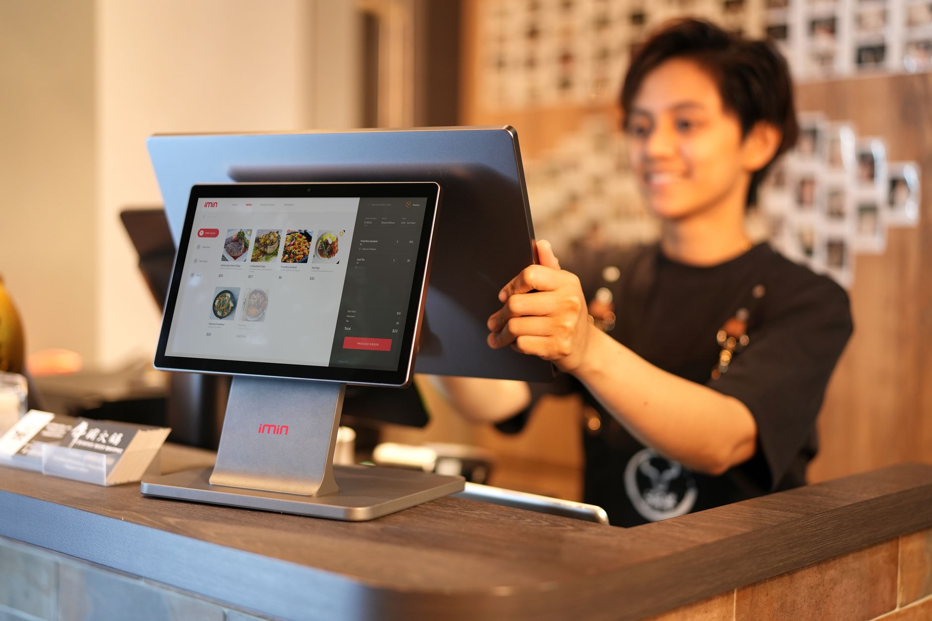 微信收款码和POS机区别在哪：Smiling cashier using a touchscreen POS syste
