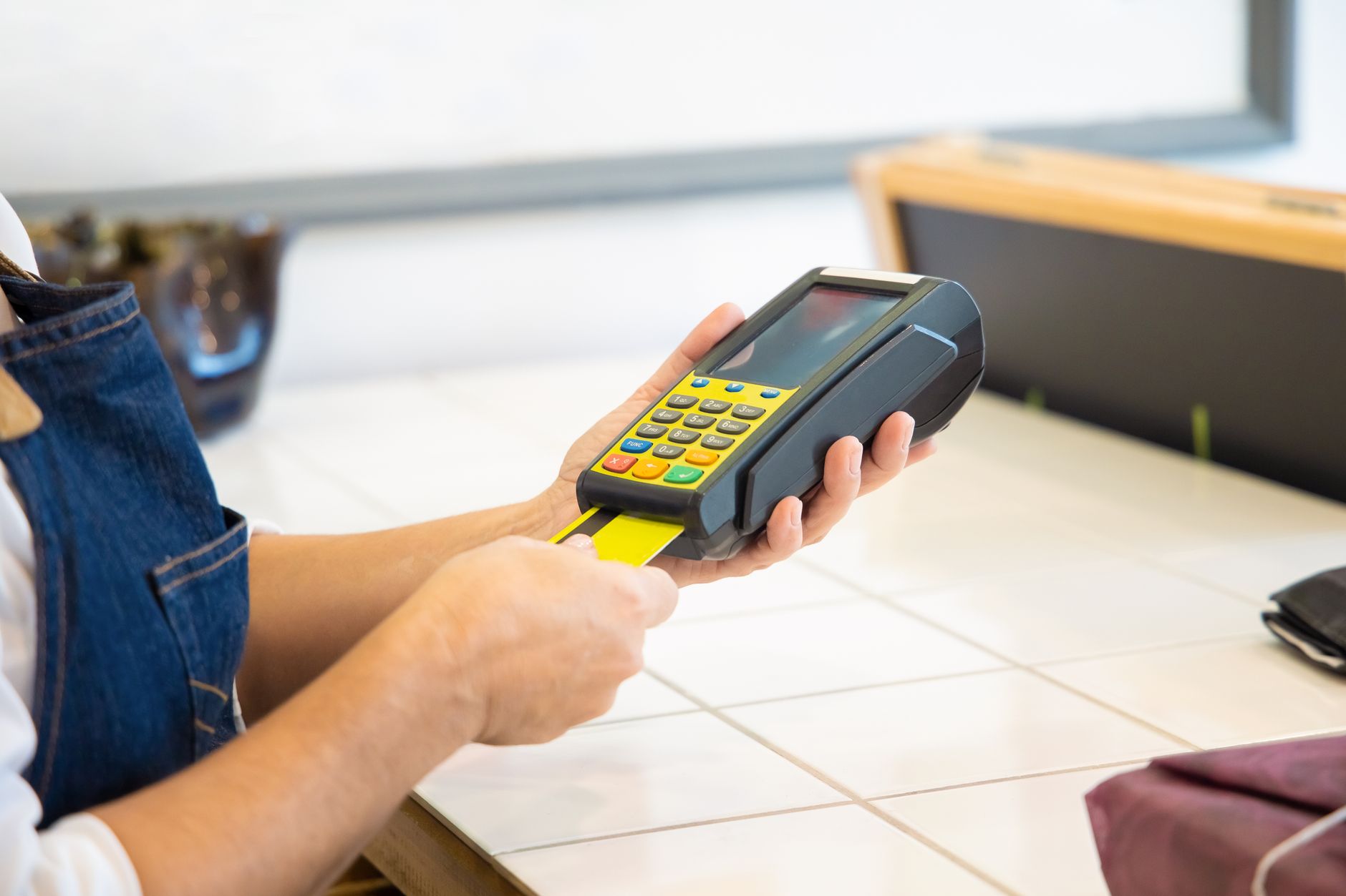 POS机一年要花多少钱:Close-up of hands operating a credit card POS ma POS机一年要花多少钱:Close-up of hands operating a credit card POS ma
